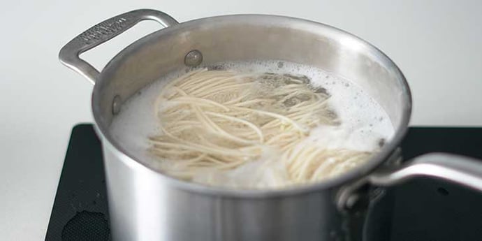 Lomein noodles being cooked to package instructions on a deep sauce pan