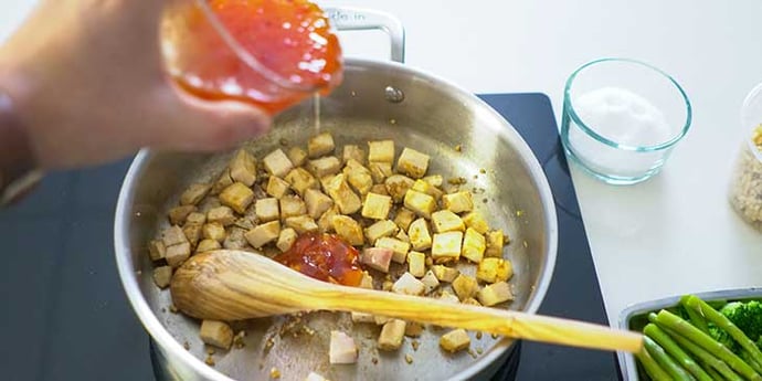 Easy Sweet and Sour Chicken Recipe being cooked on a fry pan and sweet and sour sauce being poured over