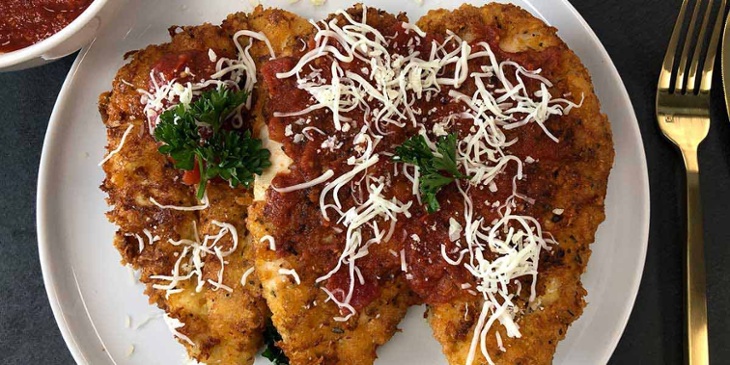 Keto Chicken Parm Recipe plated on a white round plate garnished with cheese and curly parsley 
