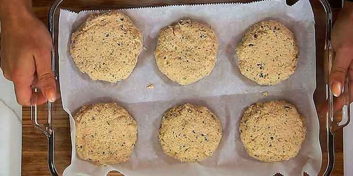 Salmon patties on a parchment paper lined glass tray