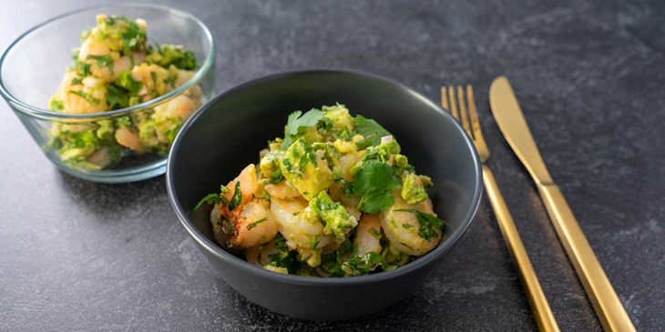 Keto Shrimp Avocado Salad Recipe plated on a glass meal prep bowl and on a black ceramic bowl next to golden silverware