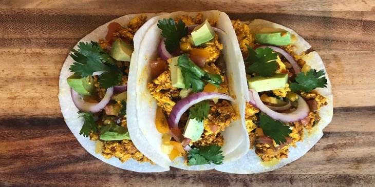 Three Low carb vegan breakfast tacos placed on top of a wooden board