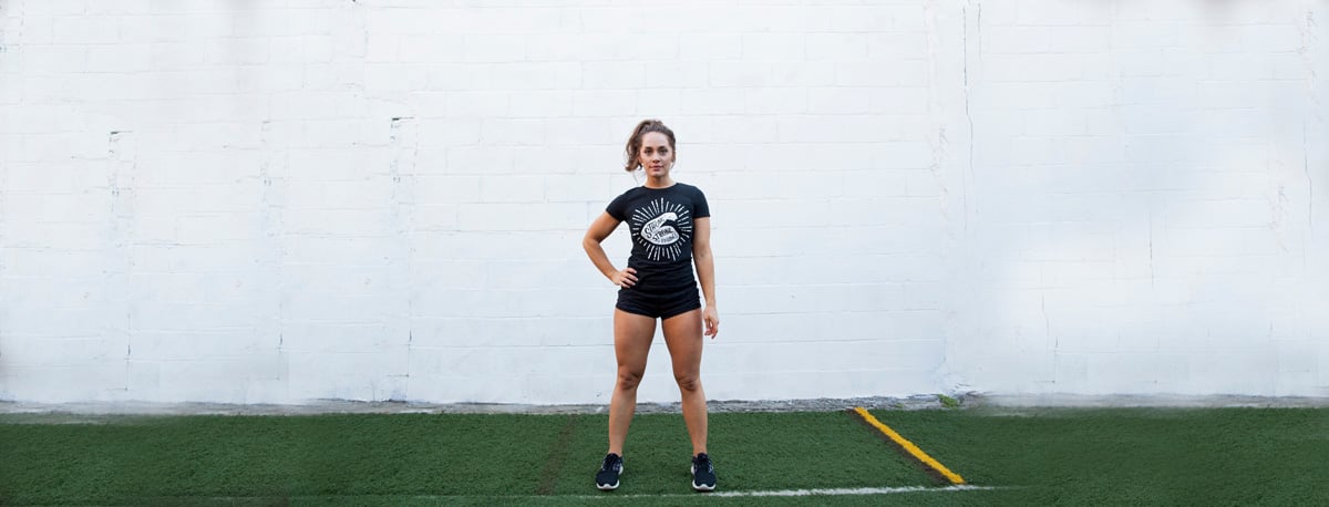 Meg Squats standing with an arm on her hip in workout clothes