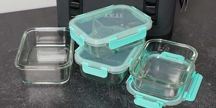 Glass meal prep containers set next to a yeti meal prep bag on a black table 