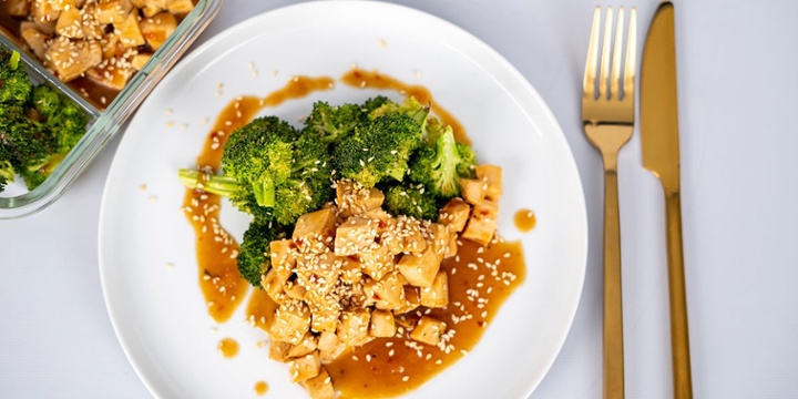 Paleo-Chicken-and-Broccoli-Recipe plated on a white plated and meal prep container served by golden utensils