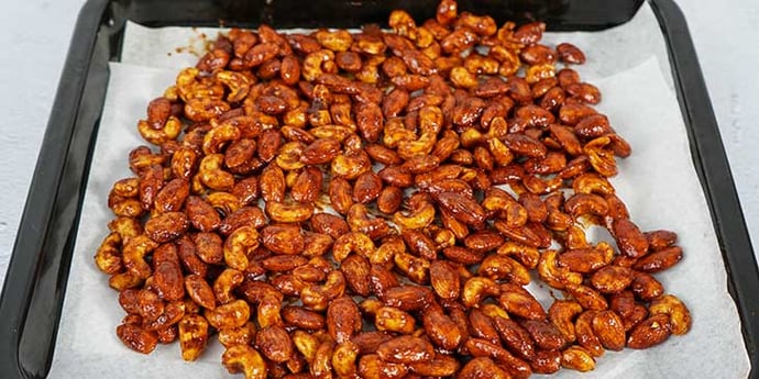 Paleo Roasted Spiced Nuts Recipe transfer seasoned nuts to a baking sheet