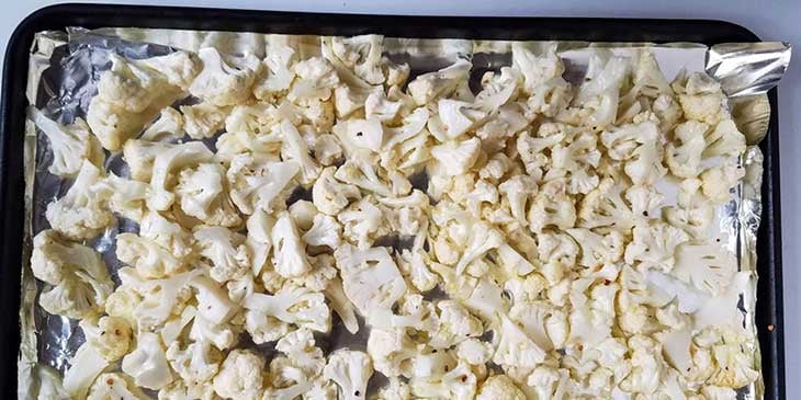 Seasoned cauliflower in a foil-lined sheet pan