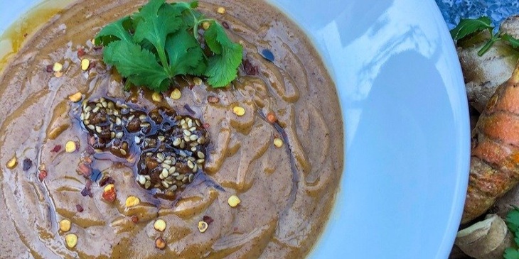 Thai Peanut-Sesame Sauce Recipe plated on a white plate with fresh turmeric and ginger next to it