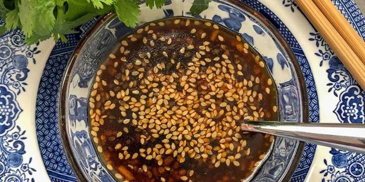 Toasted Sesame Ginger Dressing on a Chinese plateware with chopsticks placed on the side and a spoon inside the bowl