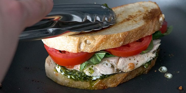 cooking chicken pesto sandwich in skillet 