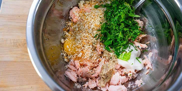 Salmon cake ingredients mixed in a shallow stainless steel bowl