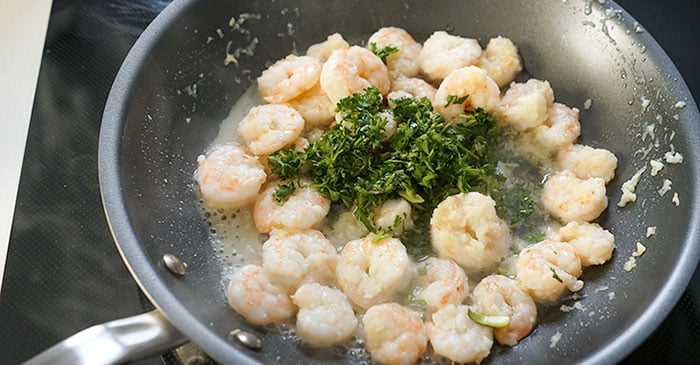 sauteing garlic shrimp in a pan with herbs