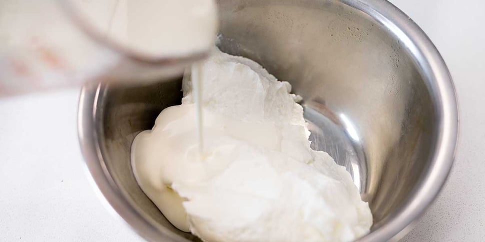 pouring heavy cream into yogurt for keto parfait 