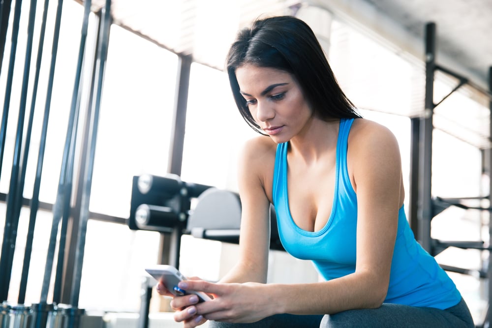 Woman using smartphone at gym