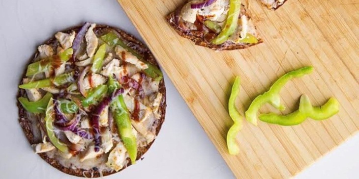 Keto bbq chicken pizza with cauliflower crust placed next to a wooden cutting board