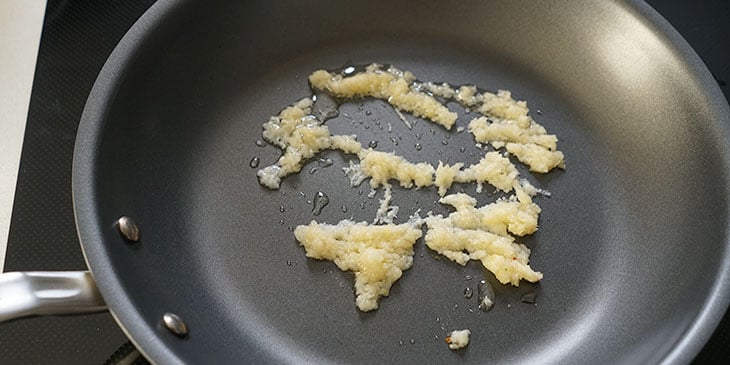 Garlic and ginger being cooked in a non-stick pan