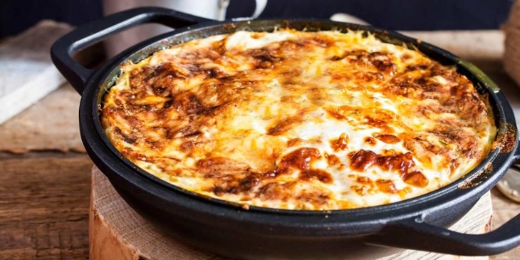 Sweet potato turkey breakfast casserole on a cast iron skillet on top of a wood background