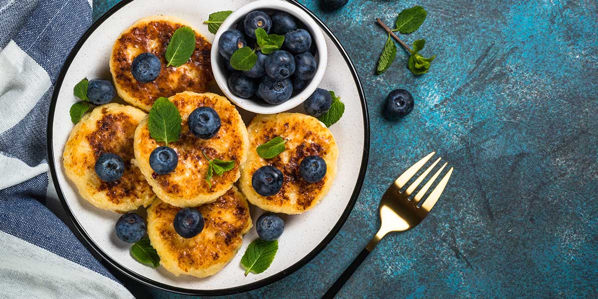 Fluffy Keto Pancakes Recipe Served on a White Plate with Berries on Top and mint leaves