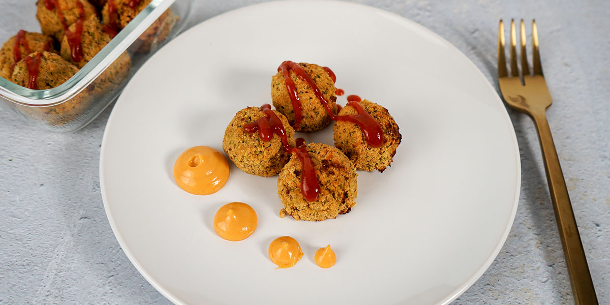 Paleo Broccoli Crispy Tots plated on a white plate with a creamy sauce in dots and sriracha on top