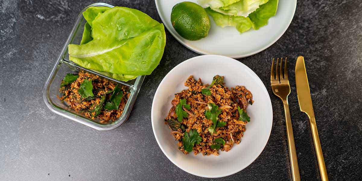 Paleo Thai Turkey Larb Recipe served on white plates with golden silverware and a meal prep container on the side