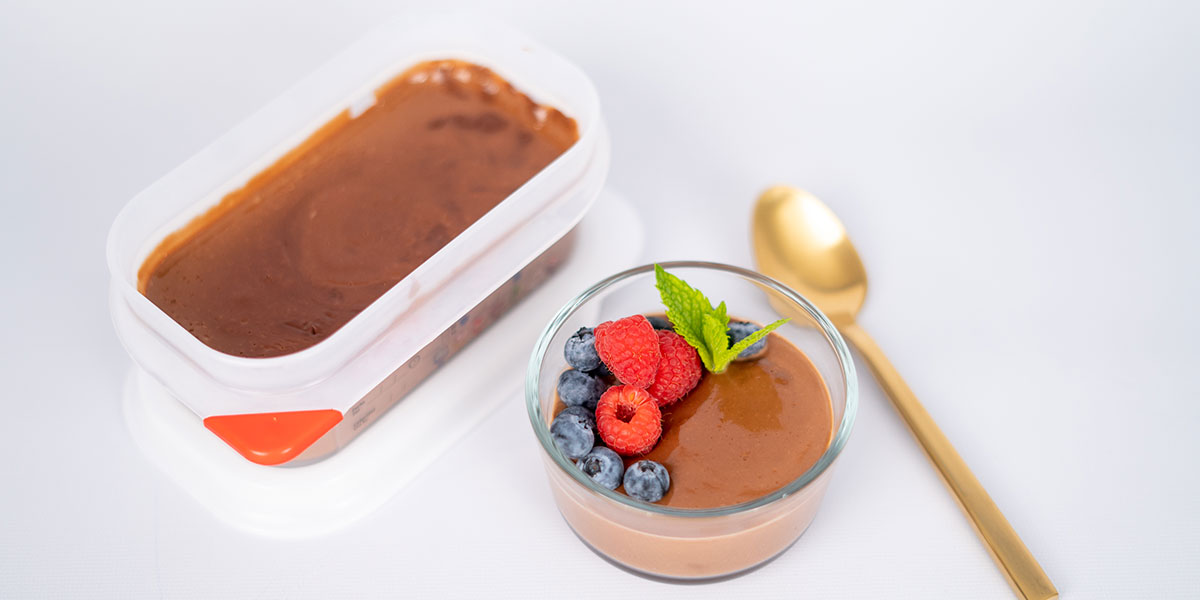 Paleo Chocolate Protein Pudding Recipe On A Tupperware and Portioned with a Golden Spoon